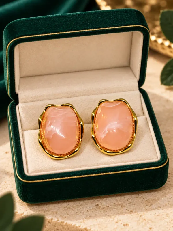 Blush pink and gold stud earrings displayed inside a green jewellery box