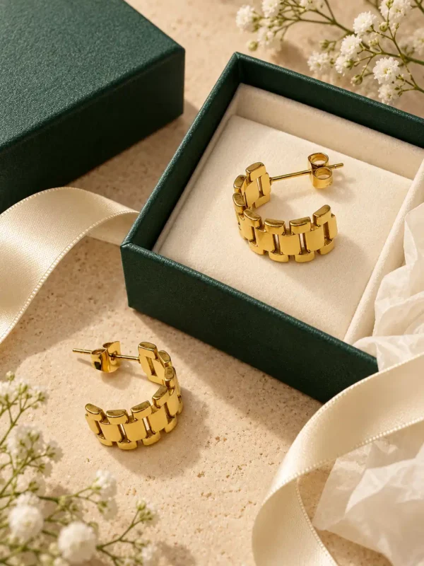 Elara gold watch-link hoop earrings styled with green jewellery box and cream ribbon