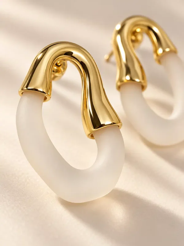 Close-up of gold-plated sculpted hoop with matte ivory resin loop