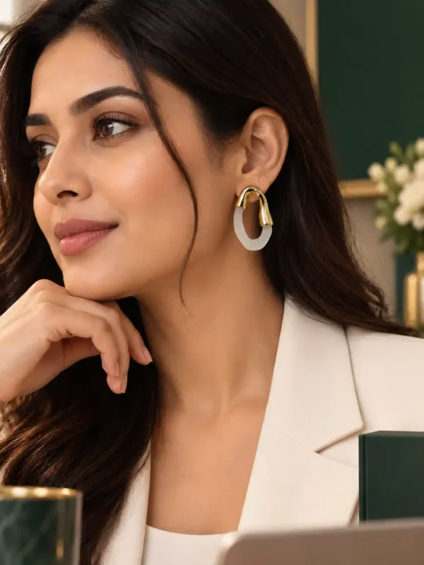Woman wearing Elara gold and ivory sculpted hoop earrings with white blazer