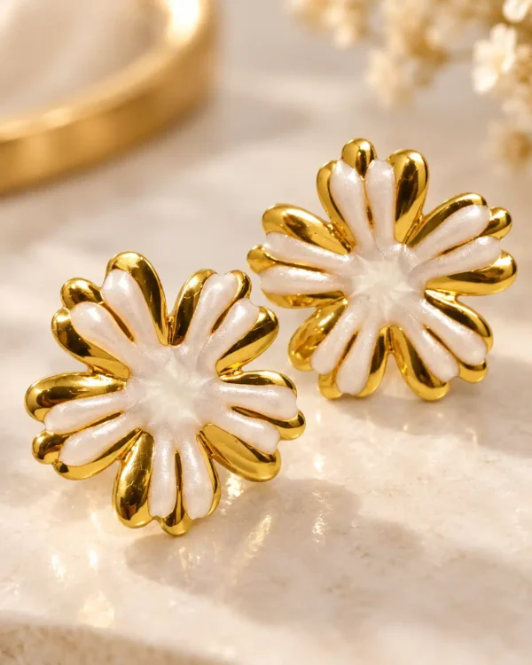 Close-up of Aurelia white enamel floral stud earrings showing layered gold-edged petal detailing