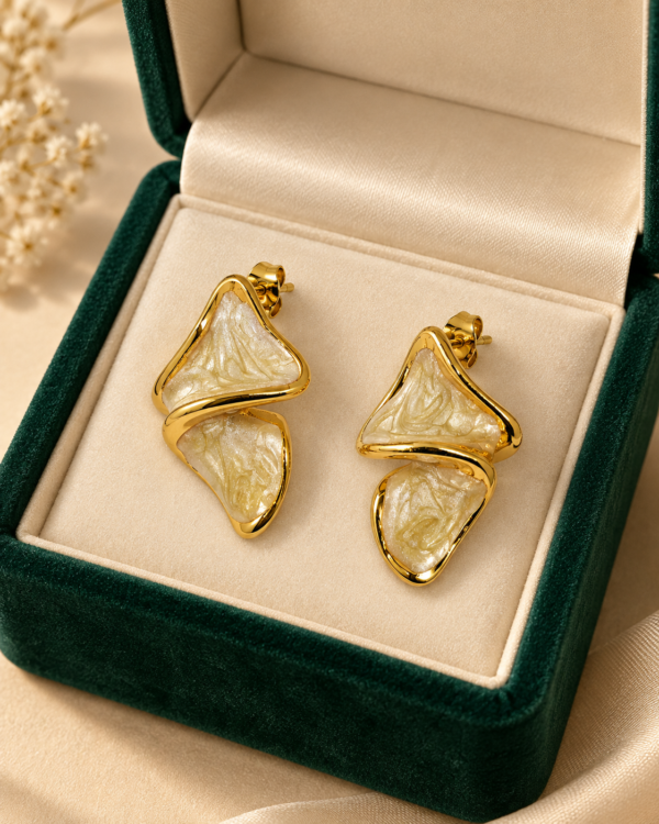 Pair of Aurelia Ripple gold and ivory stud earrings displayed inside a green jewellery box