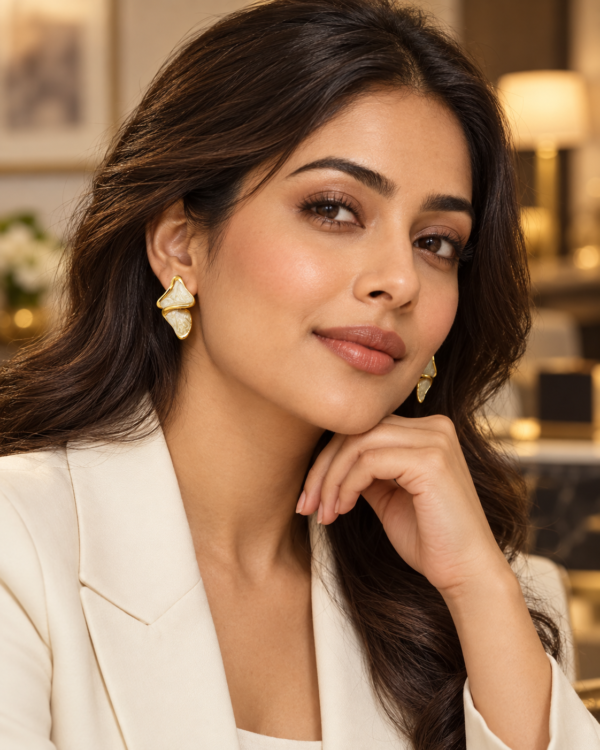 Woman wearing Aurelia Ripple gold and pearlescent ivory stud earrings with a white blazer