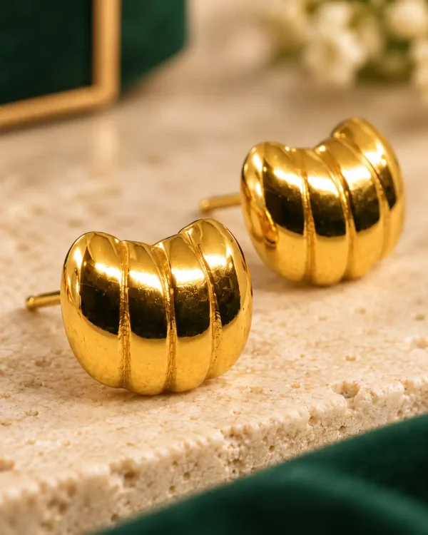 Close-up of polished gold ribbed dome stud earrings showing segmented detailing