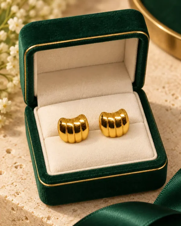 Pair of gold ribbed dome stud earrings displayed in a dark green jewellery box