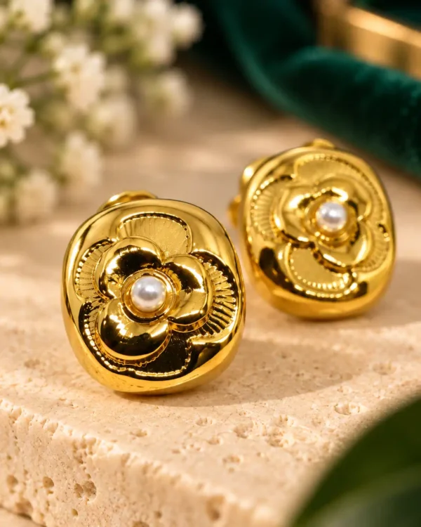 Close-up of gold Camellia Pearl Bloom stud earrings with textured flower petals and small white pearl centres