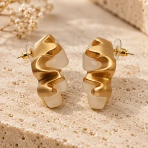 Gold-tone and translucent ivory white sculptural stud earrings with a wavy organic design