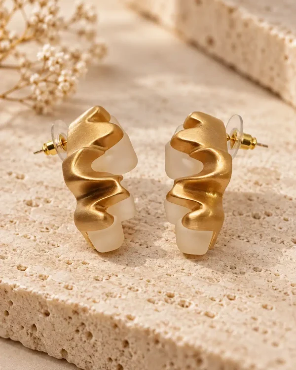 Gold-tone and translucent ivory white sculptural stud earrings with a wavy organic design
