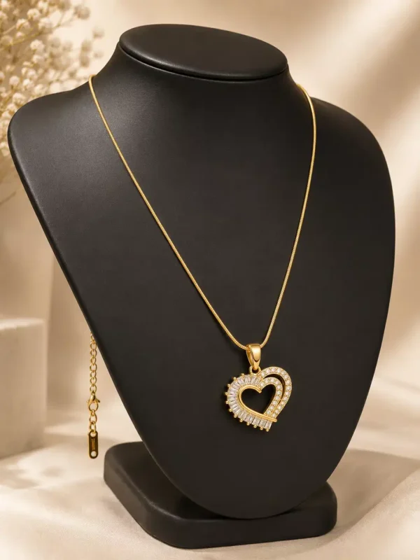 Amoura gold-tone heart pendant necklace displayed on black jewellery bust with extender chain