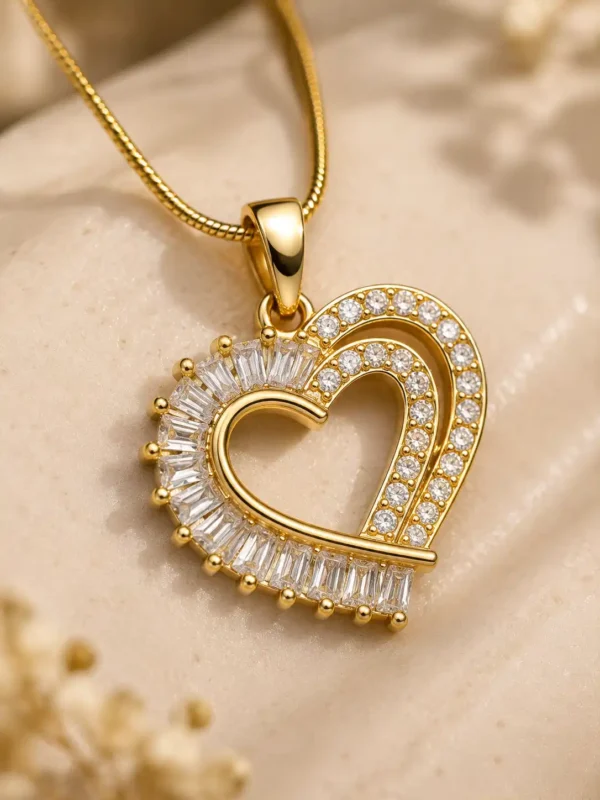 Close-up of Amoura open-heart pendant with clear baguette and round CZ stones in gold-tone setting