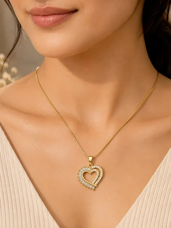 Woman wearing Amoura gold-tone heart pendant necklace with clear CZ stones and cream V-neck top