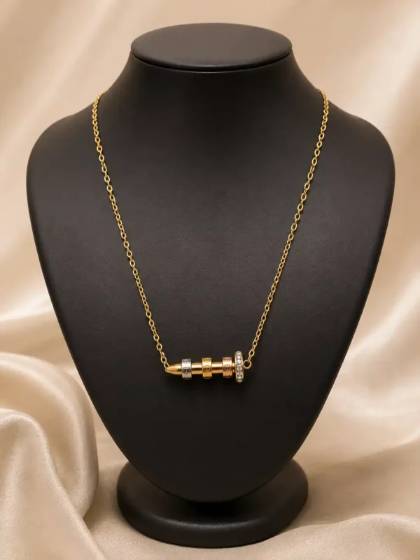Veyra gold-tone nail pendant necklace displayed on black jewellery bust with tri-tone accents