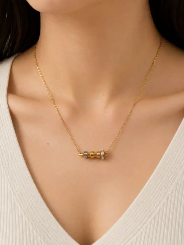 Woman wearing Veyra tri-tone nail pendant necklace with white V-neck top