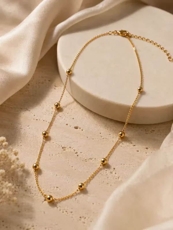 Solene gold bead station necklace with lobster clasp and extender styled on ivory stone and satin