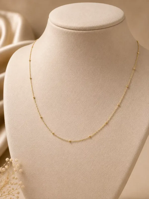 Evara delicate gold-tone tiny bead necklace displayed on ivory jewellery bust