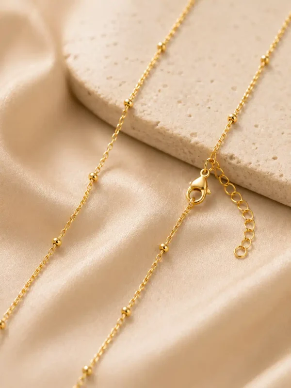 Close-up of Evara gold-tone chain with tiny bead details, lobster clasp and extension links
