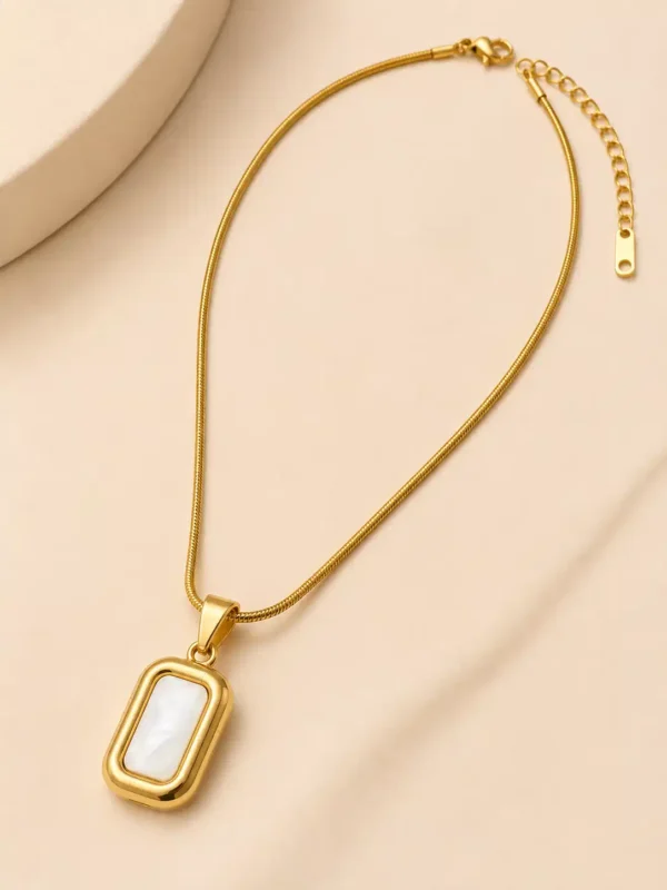 Gold mother of pearl necklace laid flat with rectangular pendant, lobster clasp and extension chain visible