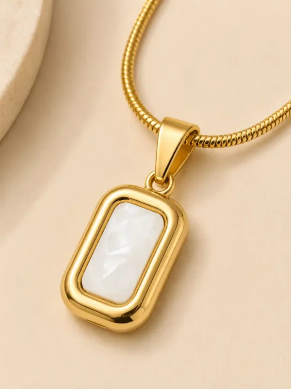 Close-up of rectangular mother of pearl pendant with polished gold-tone frame on a snake chain