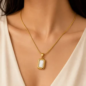 Woman wearing a gold mother of pearl pendant necklace with a rectangular white pendant and slim snake chain