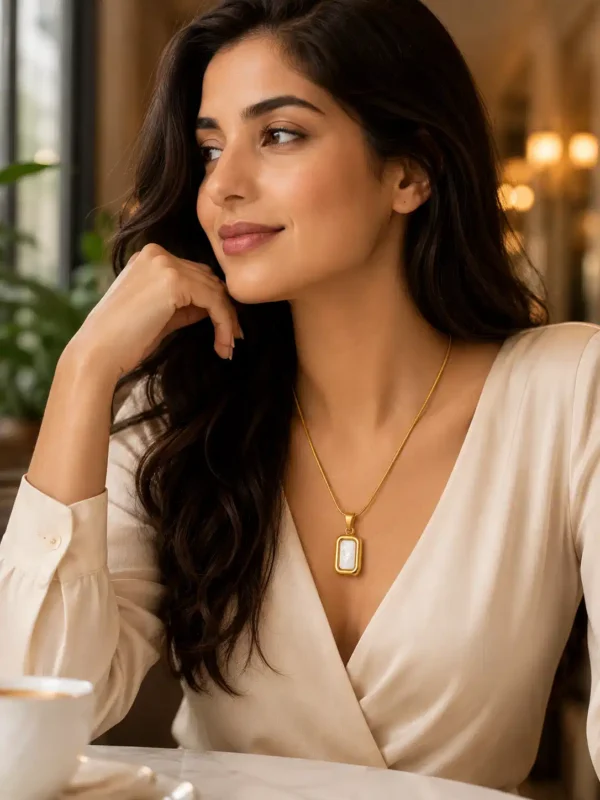 Woman styling a gold mother of pearl pendant necklace with an elegant cream outfit for everyday wear