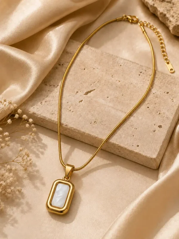Gold mother of pearl pendant necklace styled on cream satin and stone with an adjustable extension chain