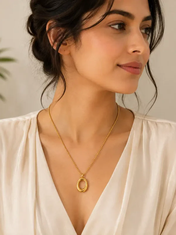 Woman styling Elara Loop gold oval pendant necklace with a neutral outfit