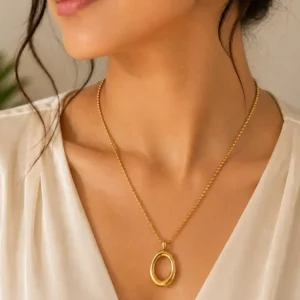 Woman wearing Elara Loop anti-tarnish gold oval pendant necklace