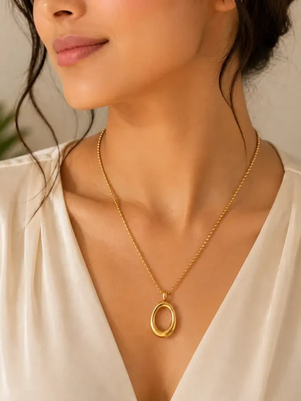 Woman wearing Elara Loop anti-tarnish gold oval pendant necklace