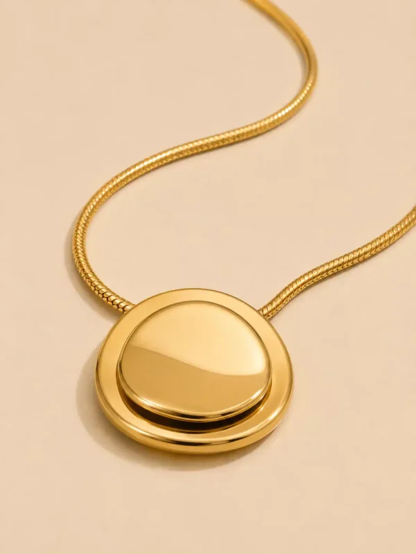 Close-up of Blume Golden Orbit layered round gold pendant with raised polished domed centre