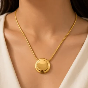 Woman wearing Blume Golden Orbit gold-tone round pendant necklace on a slim snake chain