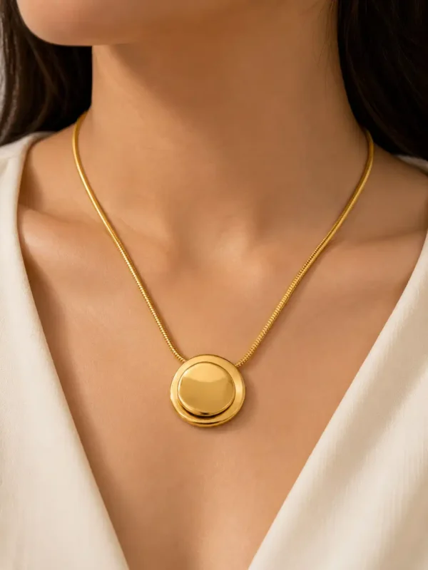 Woman wearing Blume Golden Orbit gold-tone round pendant necklace on a slim snake chain