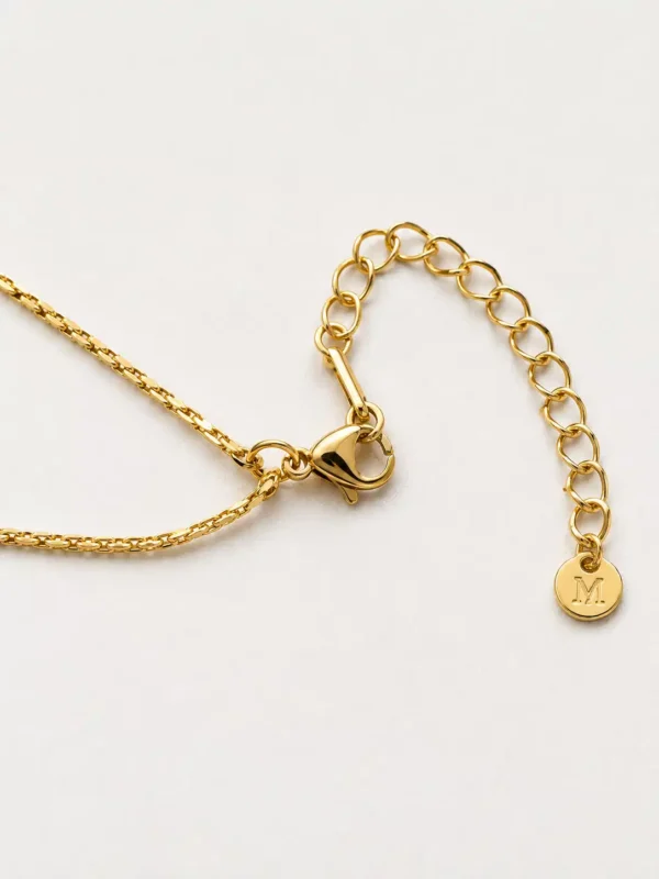 Muse pendant necklace lobster clasp and adjustable gold-tone extension chain with round end tag close-up