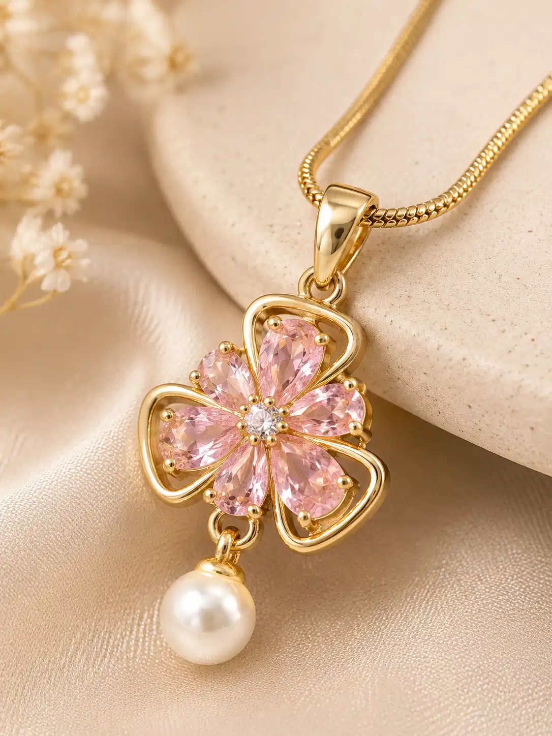Close-up of gold-tone pink crystal flower pendant with clear centre stone and pearl drop