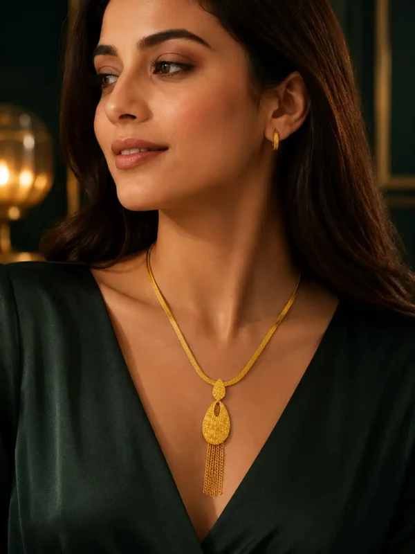 Woman wearing the Aurelia gold tassel drop necklace with a dark green evening outfit