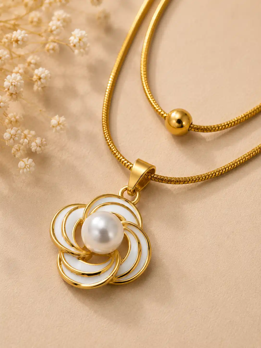 Close-up of white floral pendant with pearl-like centre on Elara gold layered necklace