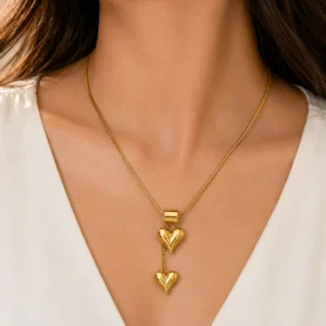 Woman wearing Amora anti-tarnish gold double heart drop necklace with puffy heart charms