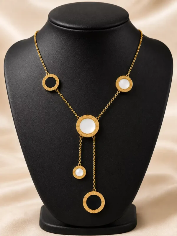 Vera gold lariat necklace displayed on black bust with white and black Roman numeral circular charms and Y drop