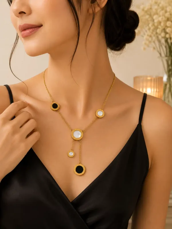 Woman styling Vera gold Y necklace with black and white circular accents and asymmetric hanging drop