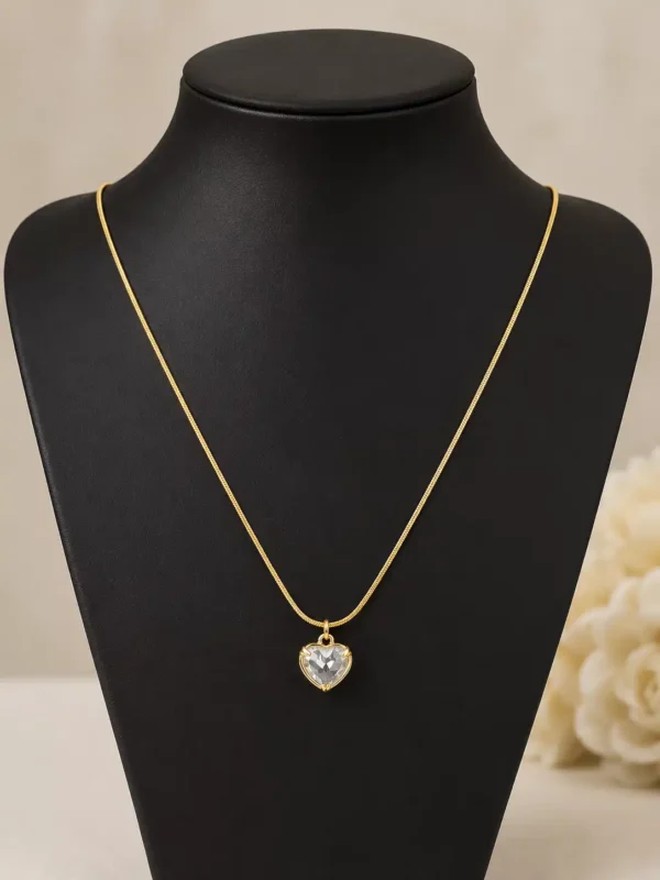 Amora gold-tone crystal heart pendant necklace displayed full length on a black jewellery bust