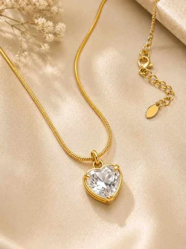Close-up of clear heart-cut crystal pendant, gold-tone snake chain, lobster clasp and adjustable extender