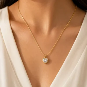 Amora anti tarnish crystal heart necklace in gold tone worn on a woman with a white V-neck outfit