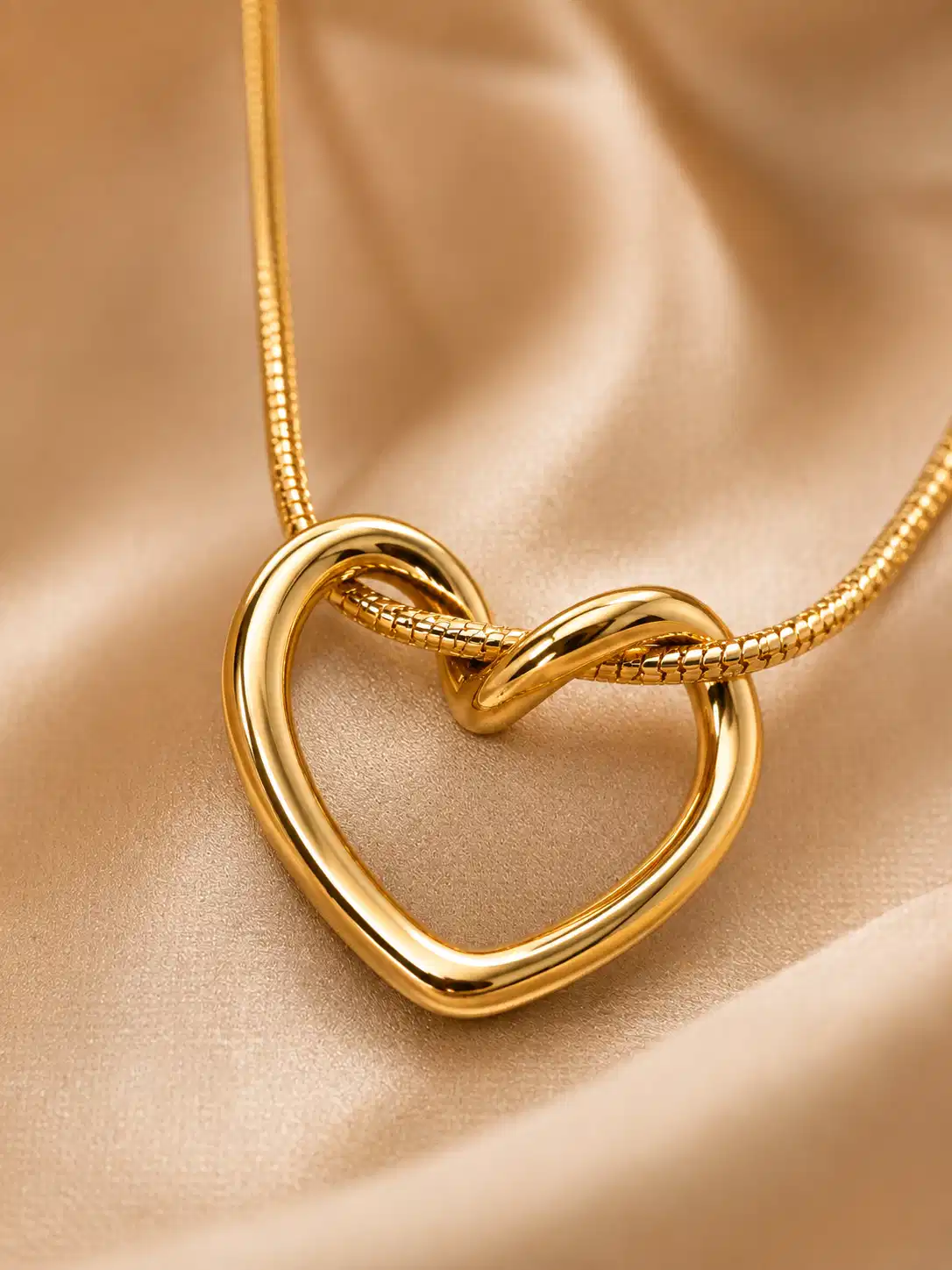Close-up of polished gold twisted open heart pendant on snake chain