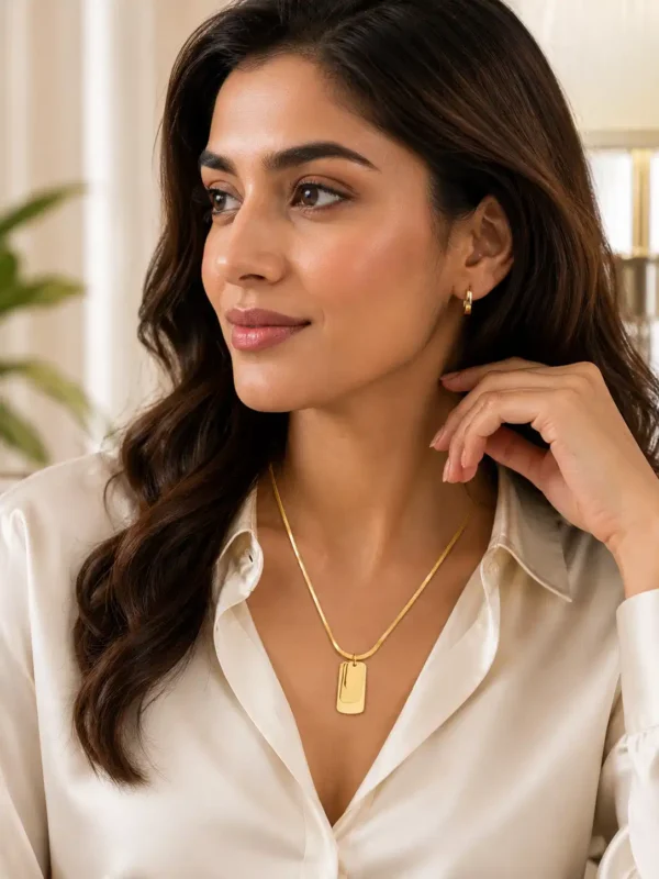 Woman wearing the Linea gold-tone layered rectangular pendant necklace with a white shirt, showing its everyday neckline scale