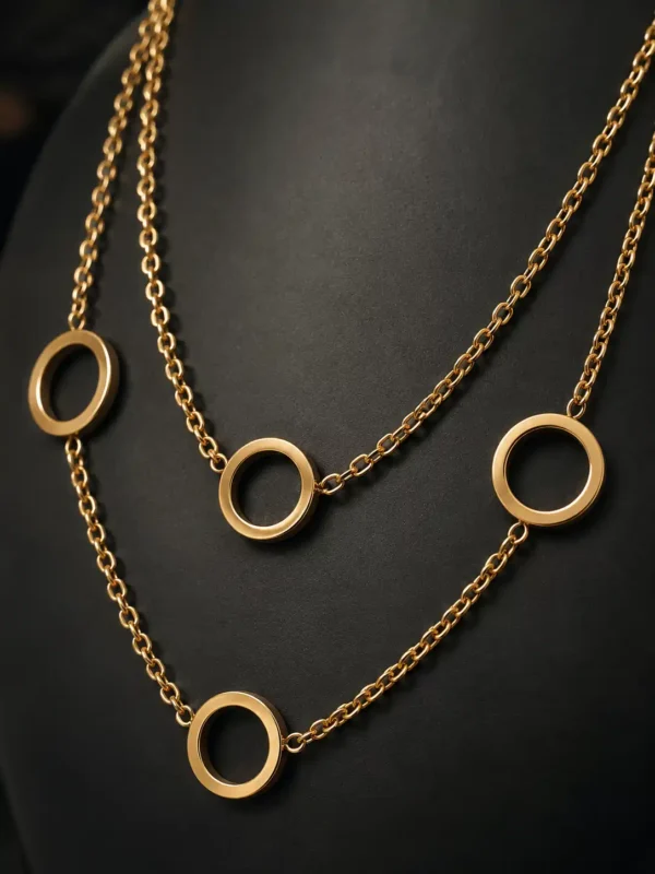 Close-up of polished open circle charms and fine gold-tone link chains on a dual-layer necklace