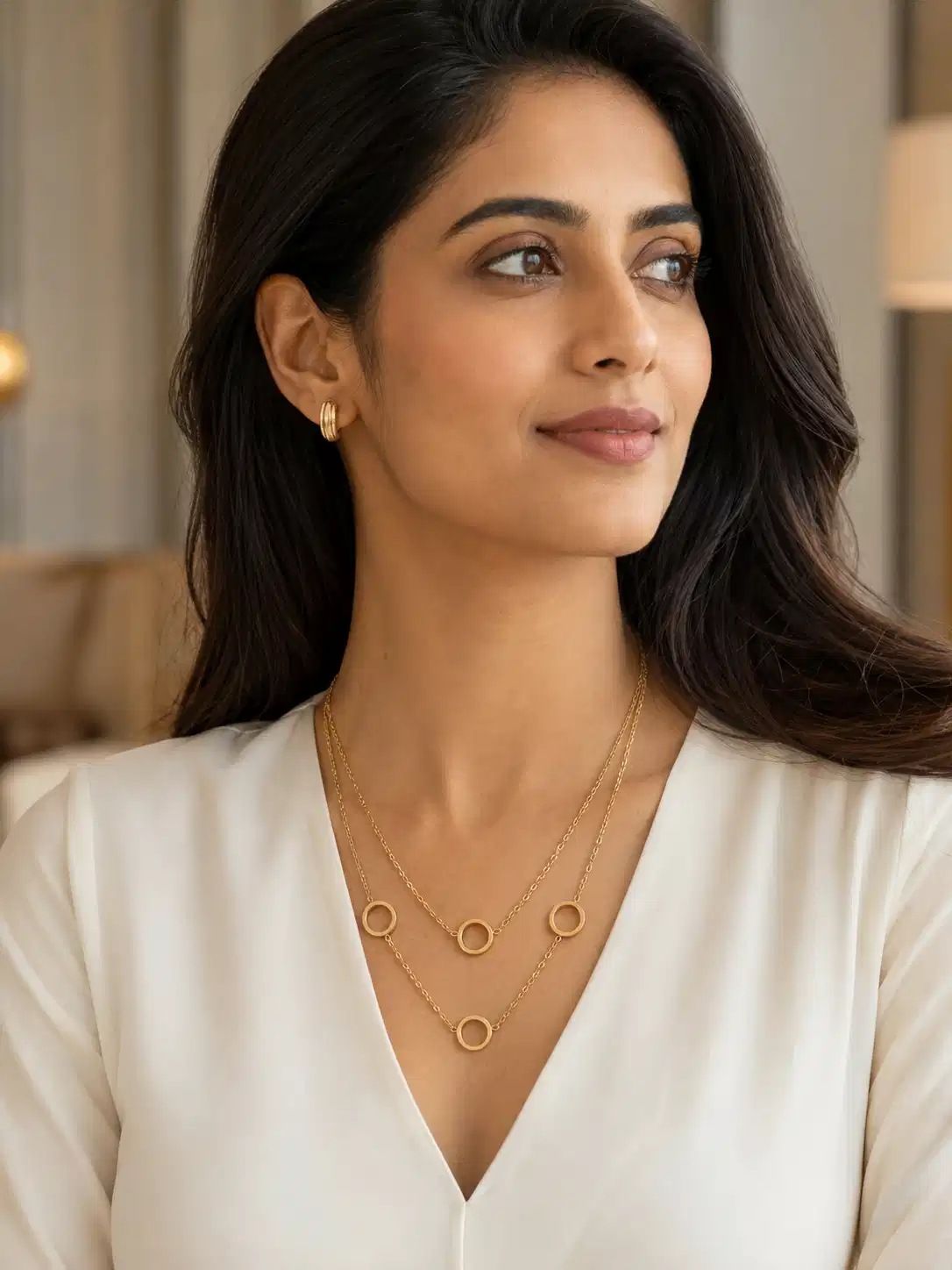 Woman in a white V-neck top wearing a gold-plated dual-layer open circle necklace for a minimal office look.
