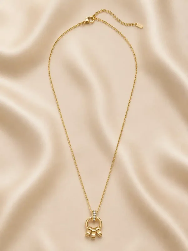 Full Elara gold pendant necklace with link chain, lobster clasp and extension chain laid on satin