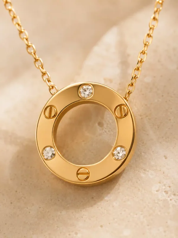 Close-up of gold circular pendant with three clear crystals and three screw motifs