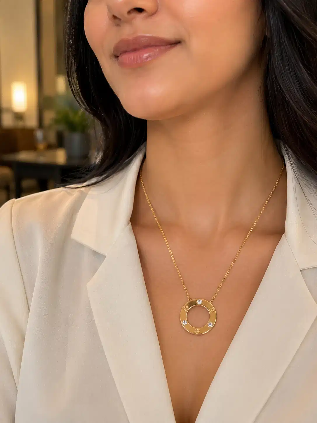 Woman wearing gold circle pendant necklace with crystal accents and white blazer