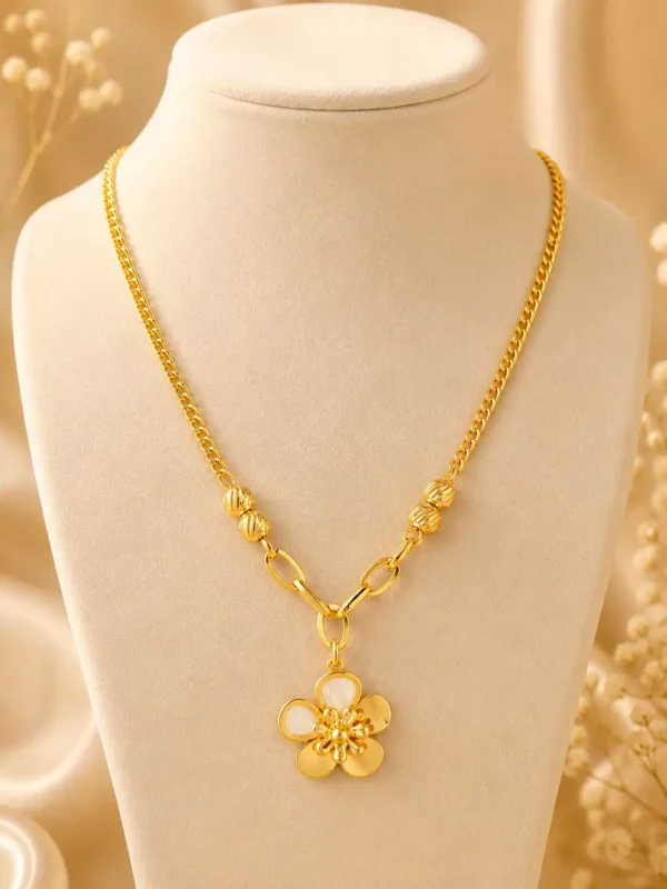 Elara Bloom gold flower pendant necklace displayed on a cream jewellery bust with textured bead and elongated link details
