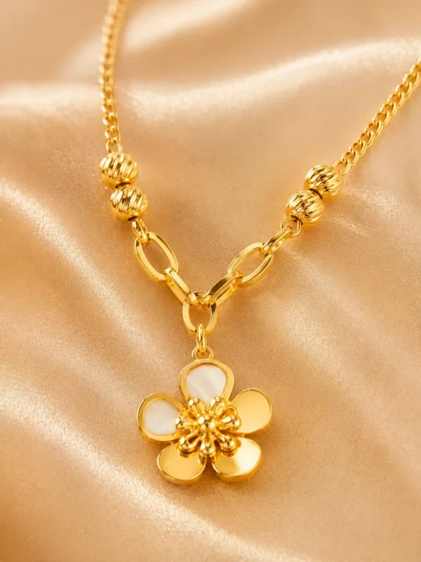 Close-up of gold flower pendant necklace with five petals, sculpted centre, ribbed beads and polished oval link details